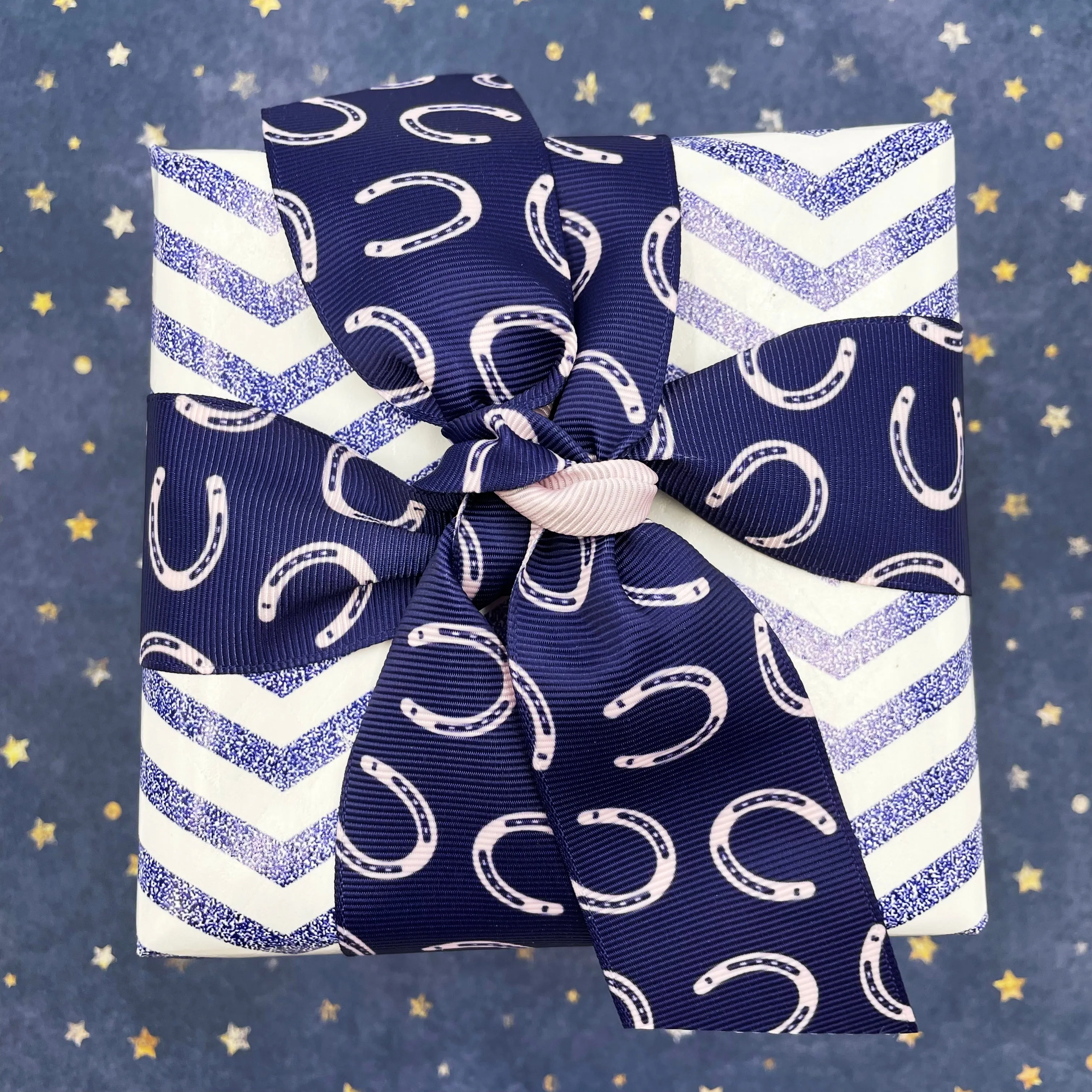 Equestrian ribbon horse shoes tossed on a navy blue  background printed on  1.5" pink grosgrain,